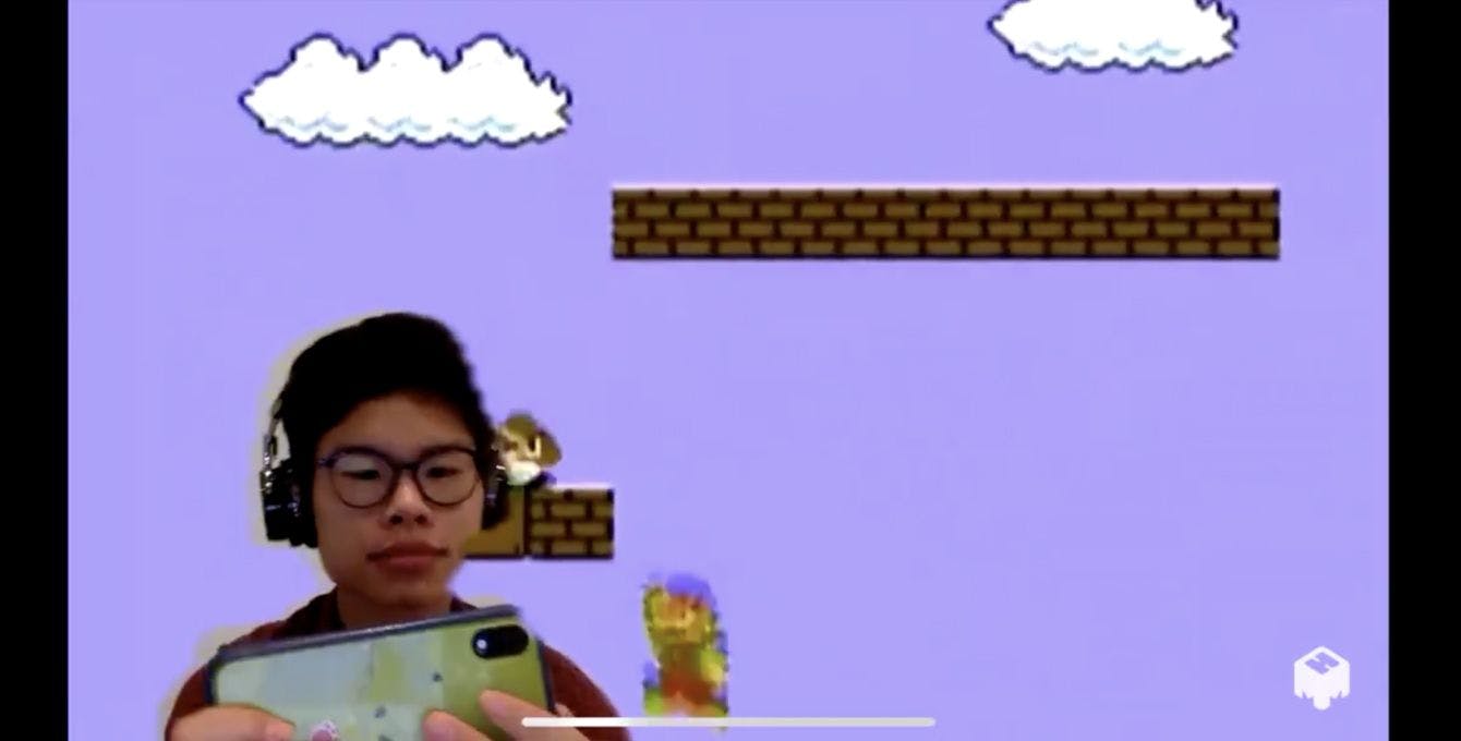 A young man playing a video game with a purple background