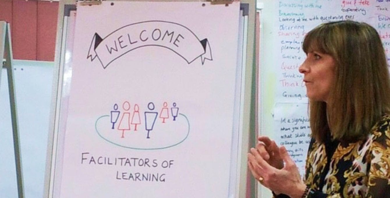 Joyce Matthews standing at the flip chart that says Welcome Facilitators of Learning